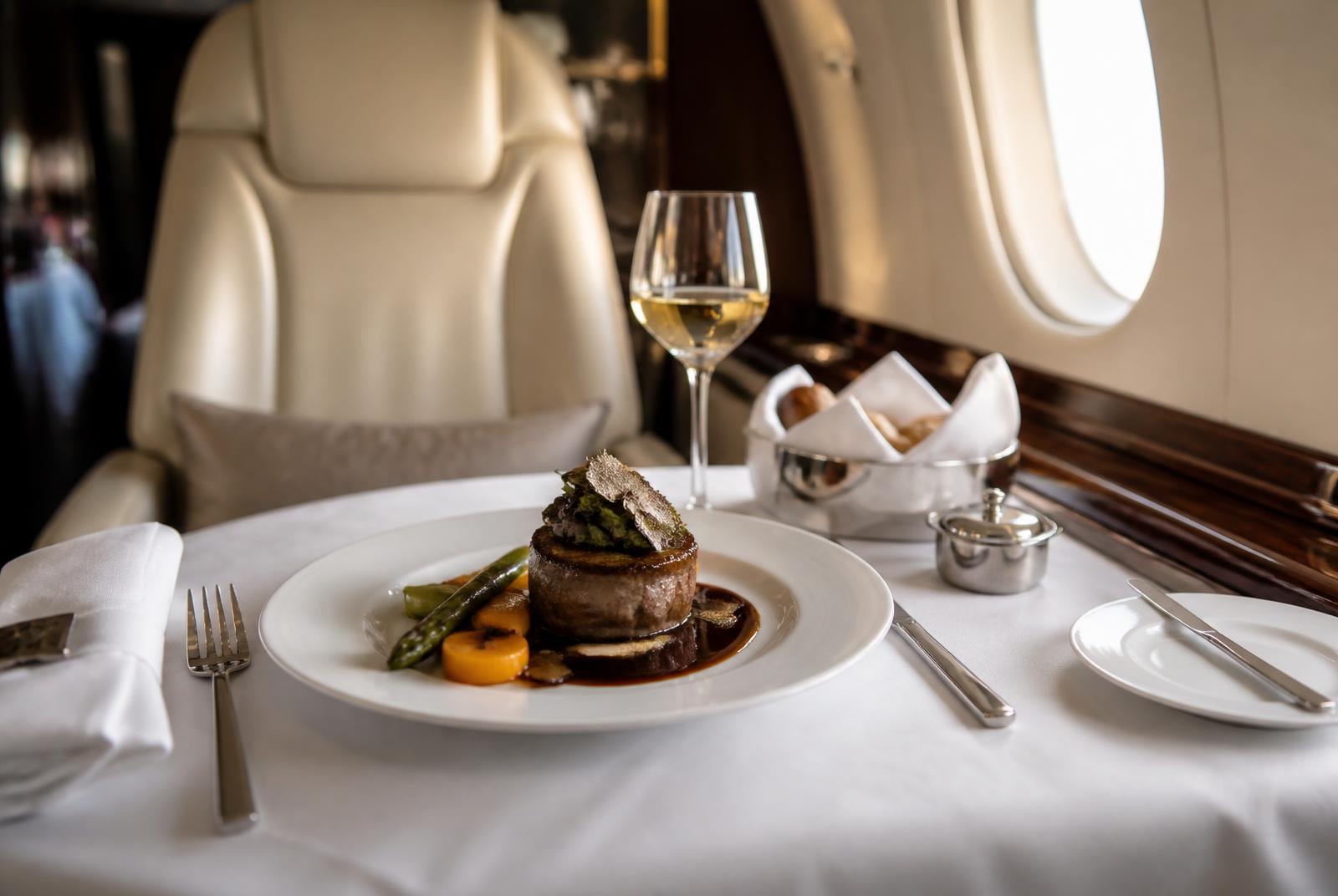 Fine dining service plated on white linen aboard a private jet